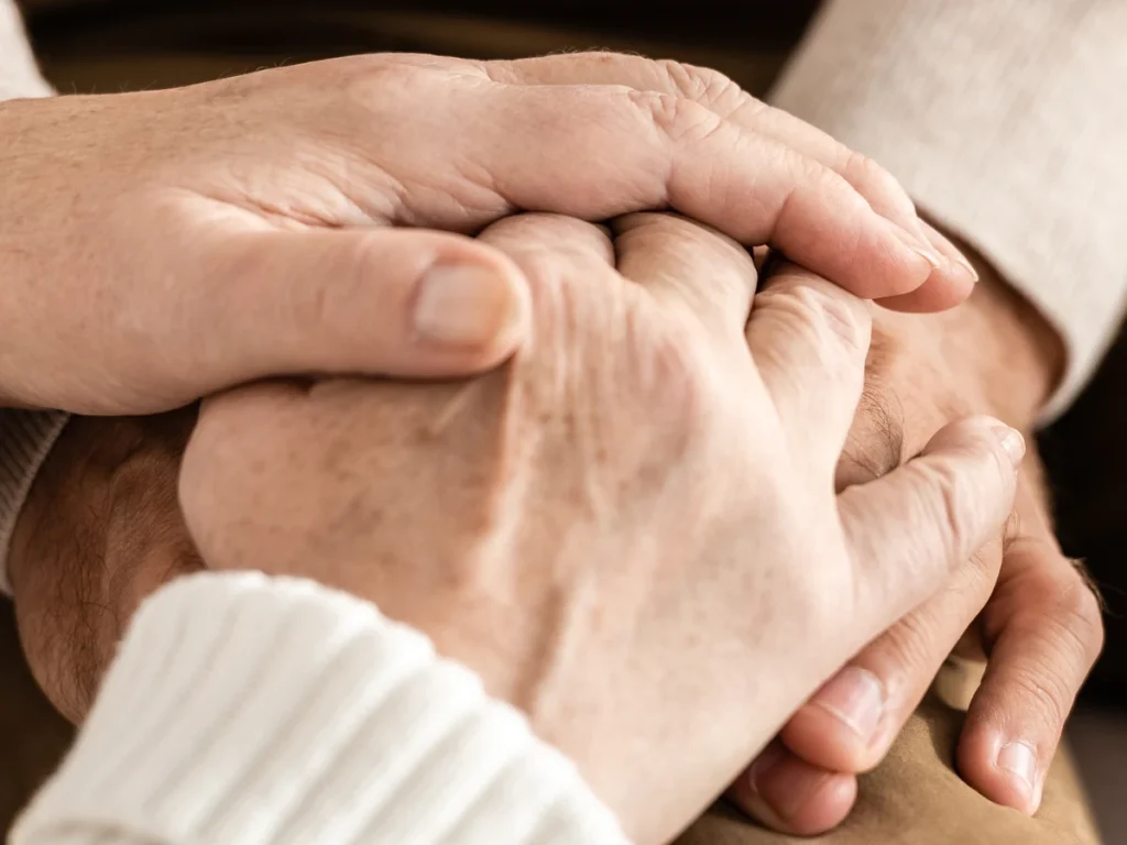 Two people holding hands in a comforting gesture
