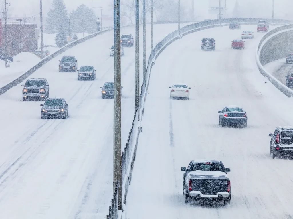 Cars and pickups driving a snowy highway during a winter storm